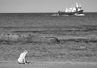 Man riding horse in sea against sky