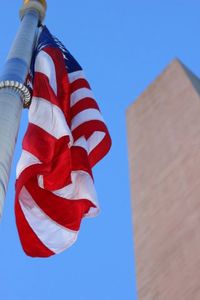 Low angle view of american flag against clear blue sky