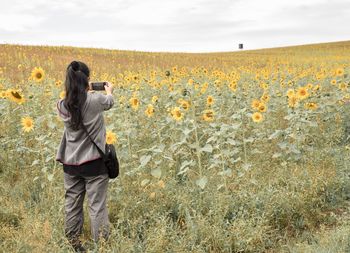 Full length of woman photographing on field