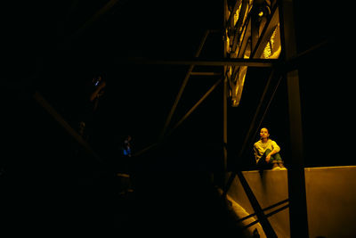 Woman sitting on bridge at night