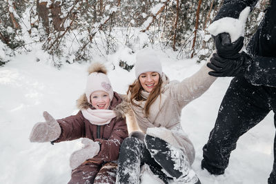 Cheerful mom and dad and daughter lying in the snow