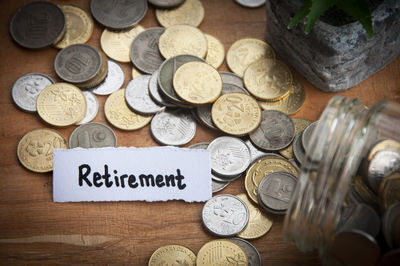 Retirement text on torn paper with coins and wooden table background. retirement concept