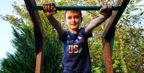 Low angle view of boy on play equipment at park