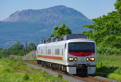 Train on railroad track by mountain against sky