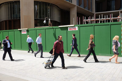 People walking on street against buildings in city