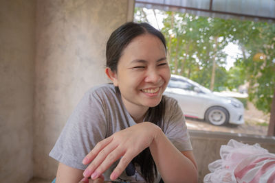 Young woman smiling while sitting on car