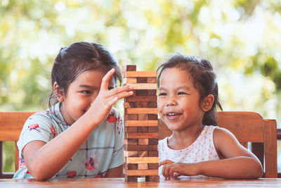 Sisters playing with wooden toy blocks on table while sitting in porch