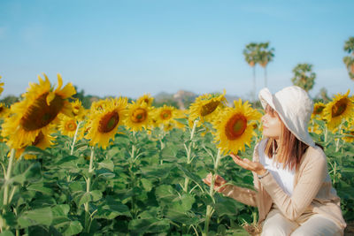 Side view of woman with sunflower against sky