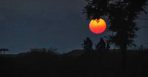 Silhouette people on field against sky at night