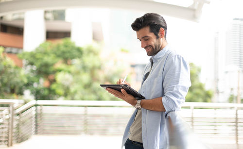 The young man uses a tablet to work at out of the office.