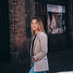 Portrait of smiling young woman standing against brick wall