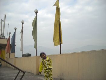 Portrait of boy standing on terrace against sky