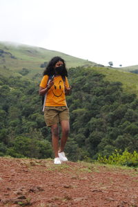 Full length of young woman standing on mountain against sky