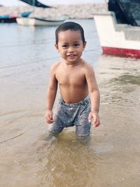 Portrait of shirtless baby boy playing in lake