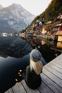 Rear view of woman sitting on pier while looking at lake 