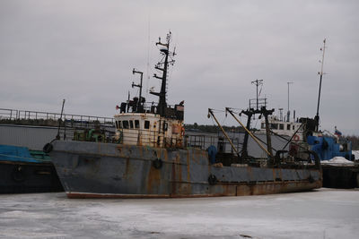 Sailboats in harbor against sky during winter