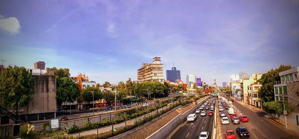 Traffic on road amidst buildings in city against sky