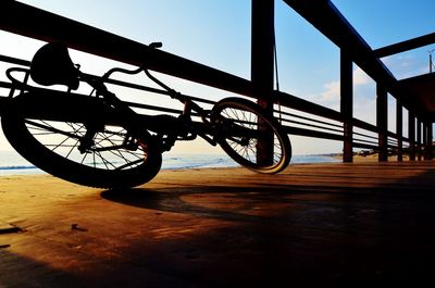 Bicycle wheel on wooden floor against sky