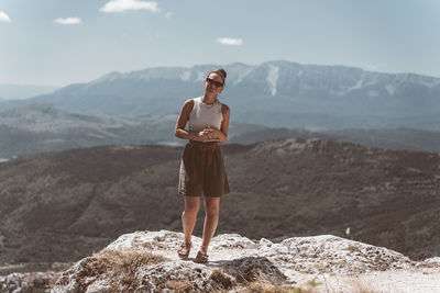 Rear view of woman standing on rock against mountain