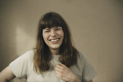Cheerful young woman against beige wall