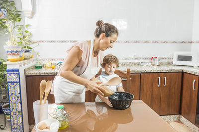 Mother and daughter standing in kitchen at home