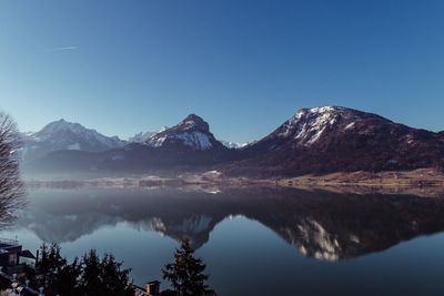 Scenic view of lake and mountains against clear blue sky