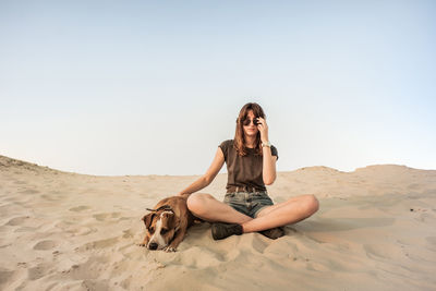Young woman sitting with dog at beach
