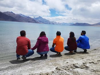 Rear view of people looking at mountains against sky