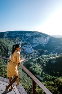 Man standing by railing on mountain against sky