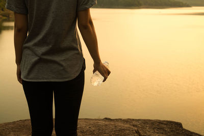 Midsection of woman standing by lake