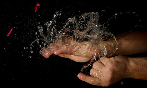 Cropped hand of man holding splashed water from exploded ballon  