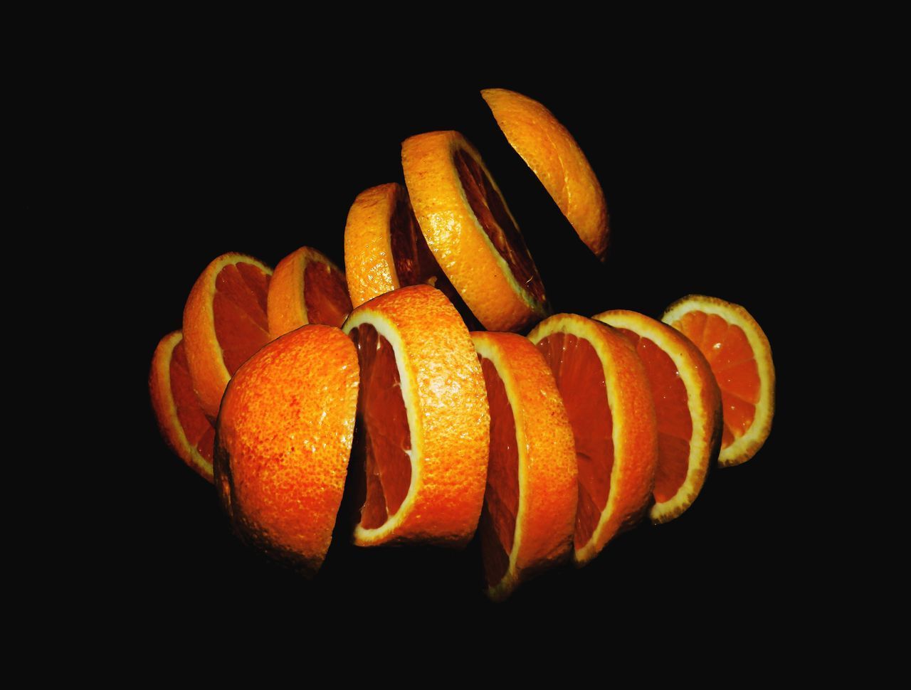 CLOSE-UP OF ORANGE SLICES OVER BLACK BACKGROUND