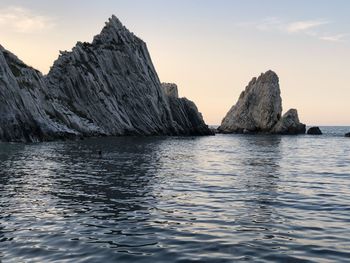 Rock formation in sea against sky