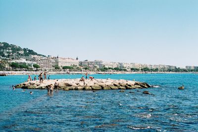 People on boat in sea against clear sky