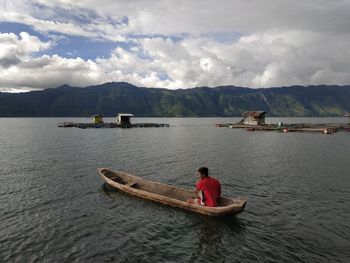 Man in boat on lake against sky