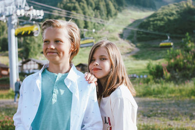 Portrait of smiling girl with brother standing on land