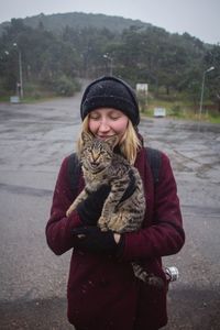 Young woman with tabby at street during snowfall