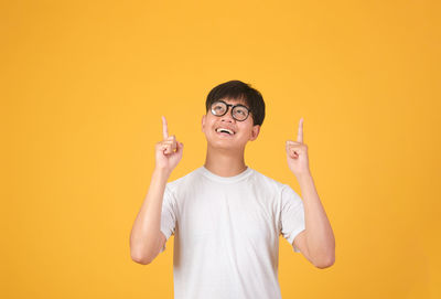 Full length portrait of boy standing against yellow background