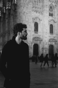 Young man looking away while standing on city street