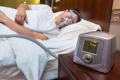 Midsection of man lying on bed in bedroom