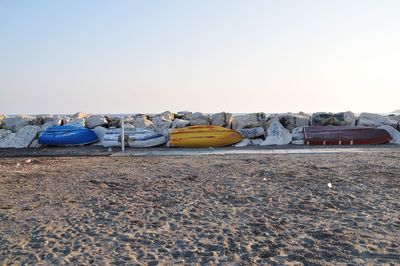 Upside down rowboats on beach against clear sky