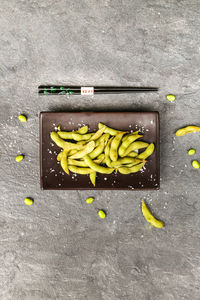 Directly above shot of broad beans in plate by chopsticks on stone tray