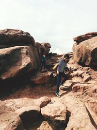 Rear view of people on rock formation against sky