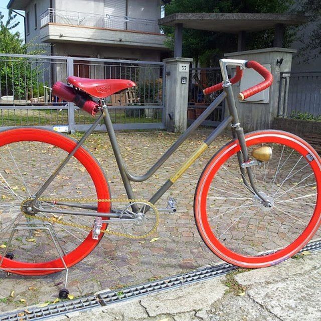 bicycle, red, transportation, land vehicle, mode of transport, built structure, wheel, stationary, building exterior, architecture, parking, metal, day, parked, outdoors, no people, sidewalk, street, railing, wall - building feature