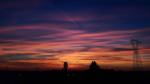 Silhouette electricity pylon against romantic sky at sunset