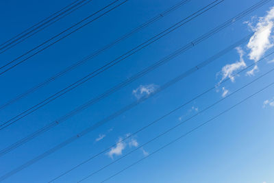 Low angle view of power lines against blue sky