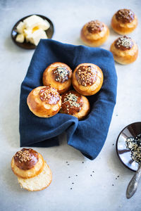 Homemade sweet yeasty buns with sugar and seeds on linen napkin. top view.