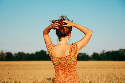 Young woman against clear sky on field