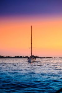 Sailboat sailing on sea against clear sky during sunset