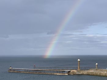 Scenic view of rainbow over sea against sky